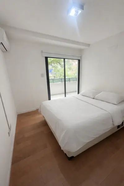 Cama minimalista en habitación luminosa.png